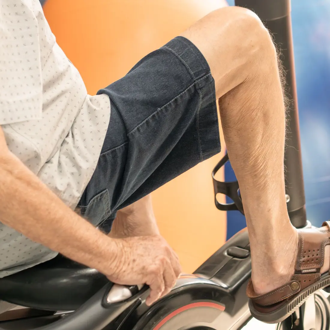 Pernas de paciente idoso pedalando bicicleta ergométrica horizontal em sessão de condicionamento