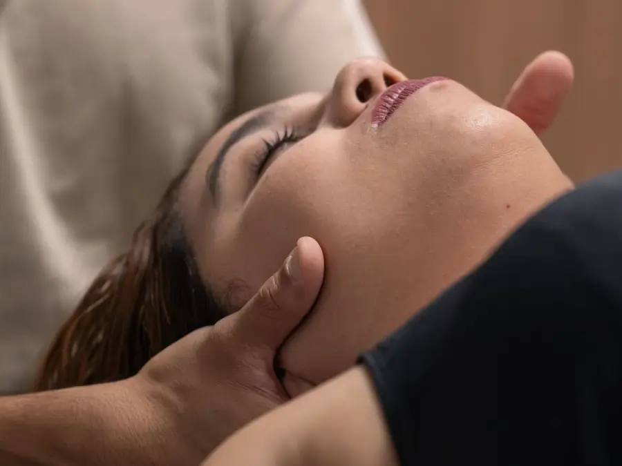Paciente relaxada recebe tração cervical manual do fisioterapeuta na maca