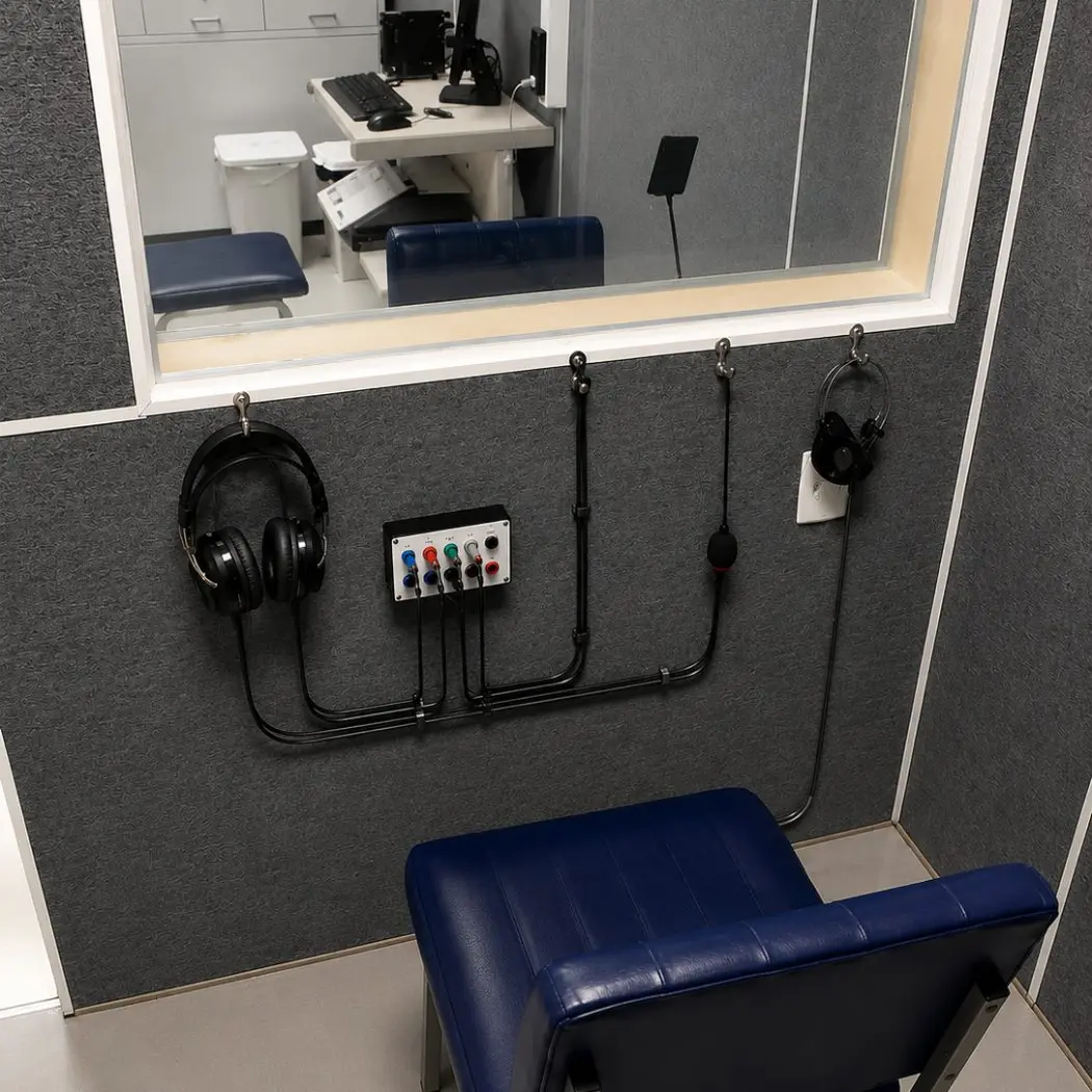 Interior da cabine acústica com poltrona e painel de conexões