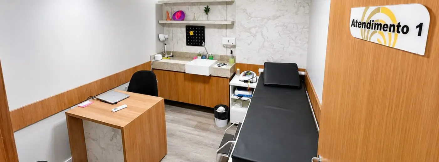 Sala de atendimento 1 da Ampiezza com mesa, maca e bancada