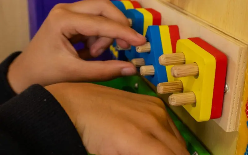Mãos de criança manipulando um painel de atividades